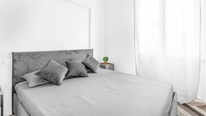 Ein modernes Schlafzimmer mit einem großen Bett, einem Nachttisch und einer kleinen Pflanze.