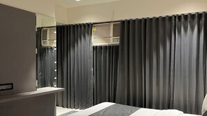 A modern bedroom with a large bed, a built-in wardrobe, and a ceiling fan. - Hotel NR INN (Ahmedabad)