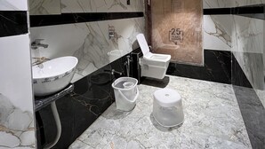 A modern bathroom with a marble sink, a toilet, and a bidet. - Hotel NR INN (Ahmedabad)