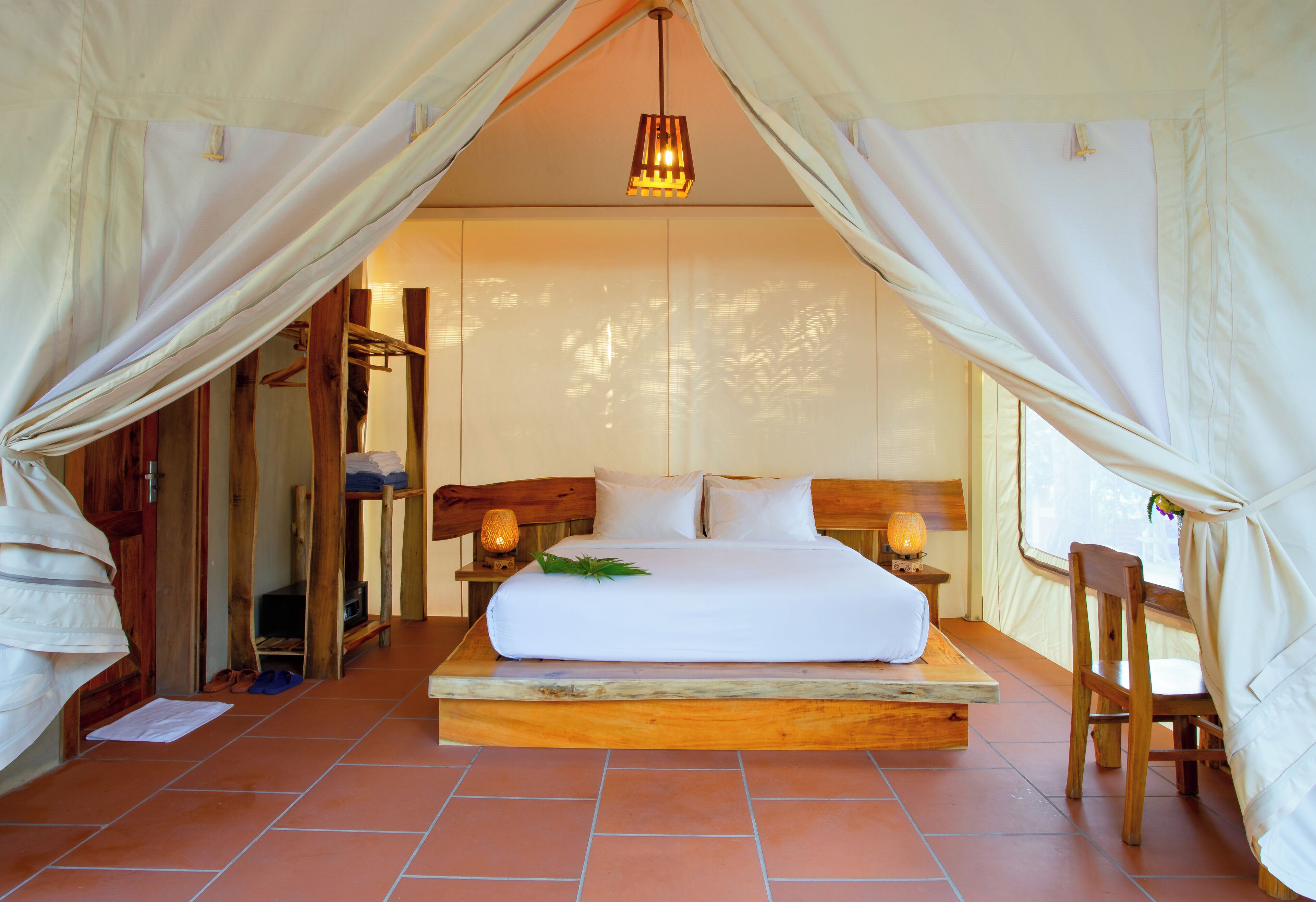 A bed with a wooden headboard, a bedside table with a lamp, and a chair.