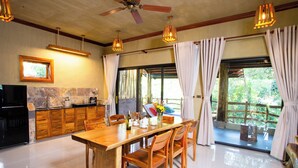 Una cocina amplia con una isla de madera, un comedor con sillas y un gran ventanal corredizo que da a un balcón.