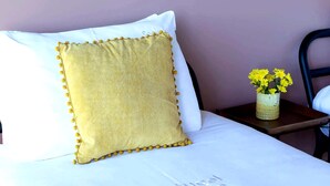 A bed with a white pillow and a textured yellow pillow with tassels. A vase with yellow flowers is on a bedside table. - Sunrise Escape with Pool by Portugal Active (Viana do Castelo)