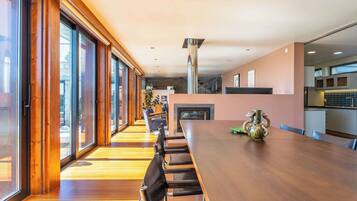 Ein modernes Interieur mit einem langen Esstisch, Holzböden und großen Fenstern.