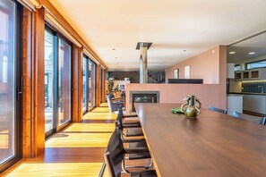 Un interior moderno con una larga mesa de comedor, piso de madera y ventanas amplias.