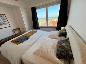 A hotel room with a bed, a chair, a window with a view, and a framed picture on the wall. - 1 bedroom accommodation in Nieuwpoort (Nieuwpoort)