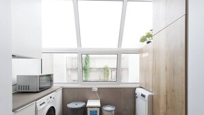 A laundry room with a washing machine, dryer, microwave, and recycling bins. - Charming 2-bedroom Apartment in Almada, Near Lisbon (Almada)