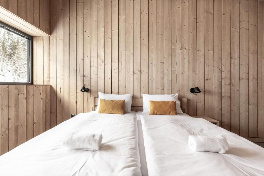 A double bed room with wooden panel walls, two bedside tables, and a window.
