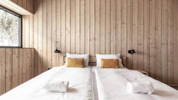 A double bed room with wooden panel walls, two bedside tables, and a window.