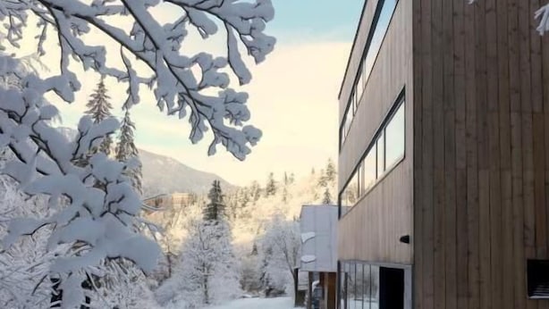 A snow-covered pathway leading to a modern building with a wooden facade and large windows. - Chata Zázvor (HORNÁ LEHOTA)