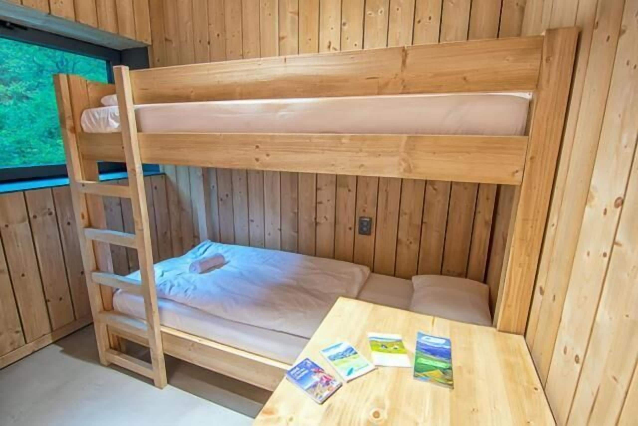 A bunk bed room with a wooden ladder and a table with cards.