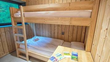 A bunk bed room with a wooden ladder and a table with cards.
