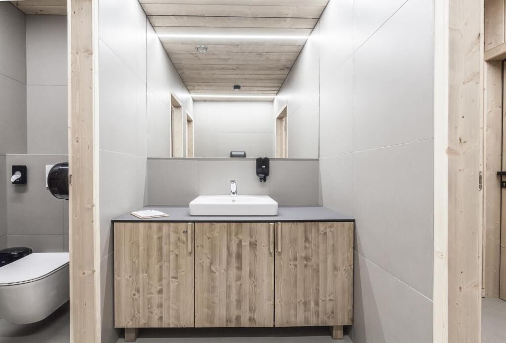 A modern bathroom with a wooden vanity, a white sink, and a mirror above it.