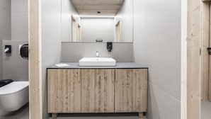 A modern bathroom with a wooden vanity, a white sink, and a mirror above it. - Chata Zázvor (HORNÁ LEHOTA)