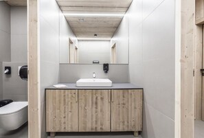 Un baño moderno con tocador de madera, un lavabo blanco y un espejo encima.