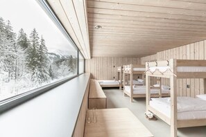 A cabin with bunk beds, a bench, and a table with glasses.