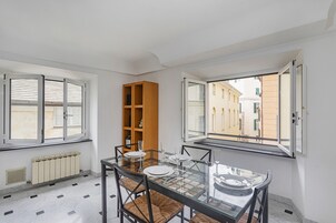 Un comedor con una mesa de vidrio, sillas y una estantería de madera.