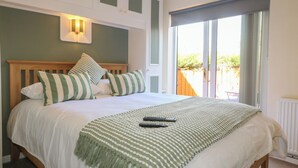 Un dormitorio con cama, almohadas, una manta y vistas al exterior.