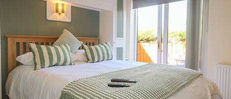 Une chambre à coucher avec un lit, des oreillers, une couverture et une vue sur l’extérieur.