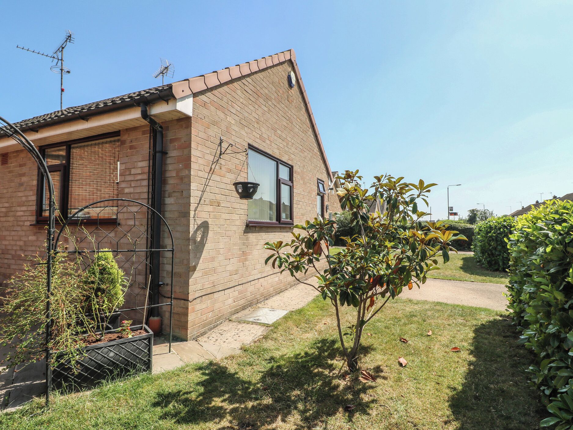 Une maison en briques avec une fenêtre, une porte et un petit arbre dans la cour.