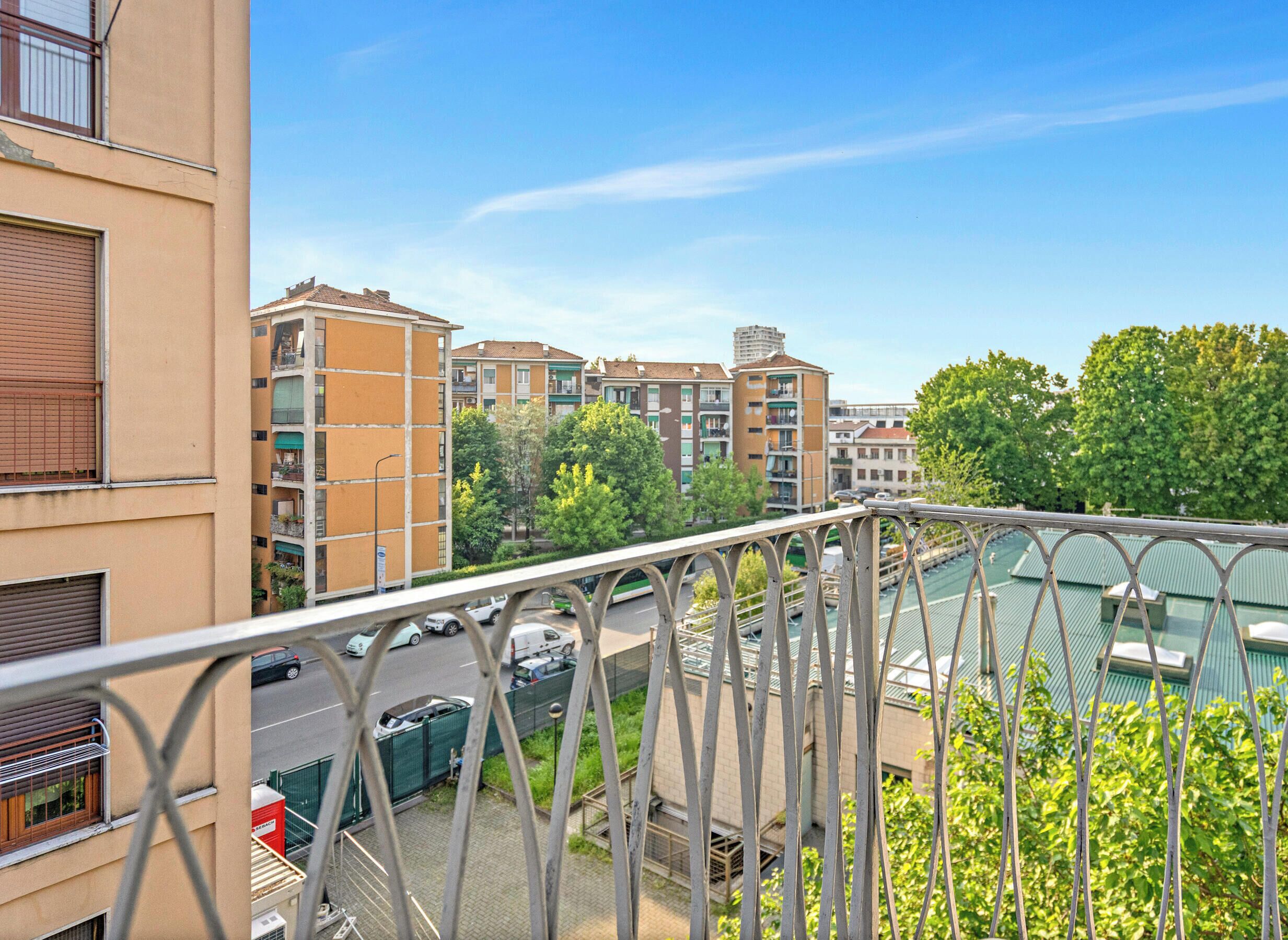 Un edificio residenziale con numerosi balconi, vista sulla strada e cielo sereno.