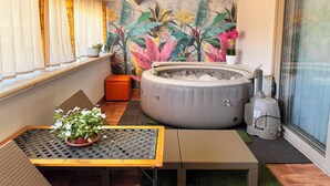 A cozy balcony with a hot tub, a table with a potted plant, and a tropical mural. - Casa Costanza 25, Argento Apartment (San Cipirello)