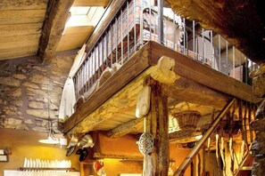 A rustic interior with a wooden balcony, stone walls, and traditional decor. - Isolated stone and timber house in the forest (Lleida)