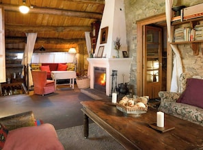 A cozy living room with a fireplace, wooden furniture, and a stone wall. - Isolated stone and timber house in the forest (Lleida)