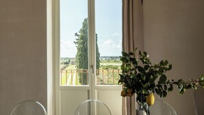 Una mesa de comedor con sillas, un florero con flores y una vista a través de una ventana.