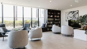 A modern interior with a large bookshelf, seating area, and large windows. - 101-251 Johnston St (Abbotsford)