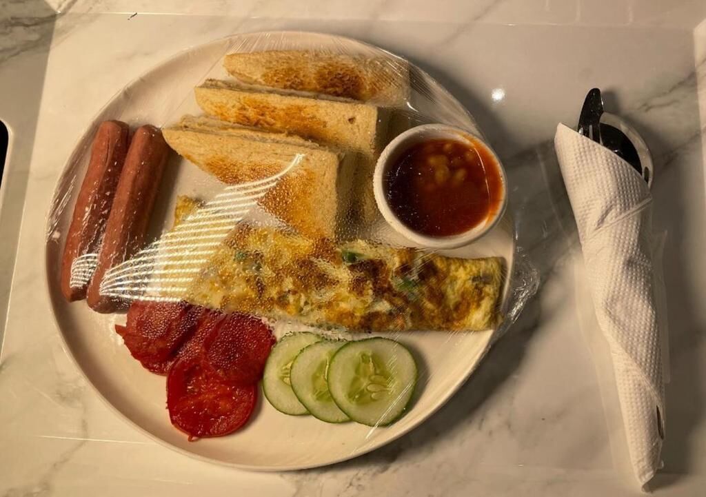 A plate with food items including hot dogs, a fried egg, and sliced cucumbers.