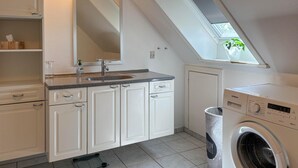 Une cuisine compacte avec des meubles blancs, un évier et un lave-linge Siemens.