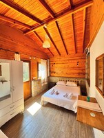 Quarto de cabana de madeira com uma cama, penteadeira e parede de pedra.