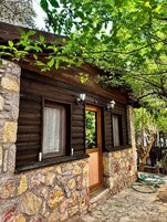 Eine rustikale Holzhütte mit Steinwänden, einer Holztür und Fenstern mit Vorhängen.