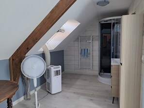 A room with a sloped ceiling, a standing fan, a white air conditioner, and a wooden cabinet. - Detached house just 5 minutes from Terrasson Lavilledieu—perfect for exploring the region! (Brignac-la-Plaine)