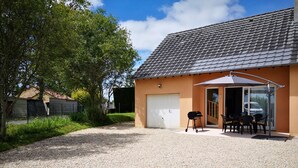 A house with a gravel driveway, a covered patio with a table and chairs, and a garage. - Detached house just 5 minutes from Terrasson Lavilledieu—perfect for exploring the region! (Brignac-la-Plaine)