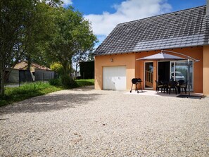 A house with a gravel driveway, a covered patio with a table and chairs, and a garage. - Detached house just 5 minutes from Terrasson Lavilledieu—perfect for exploring the region! (Brignac-la-Plaine)