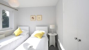 Ett hotellrum med två sängar, ett fönster, en lampa och två inramade tavlor på väggen.