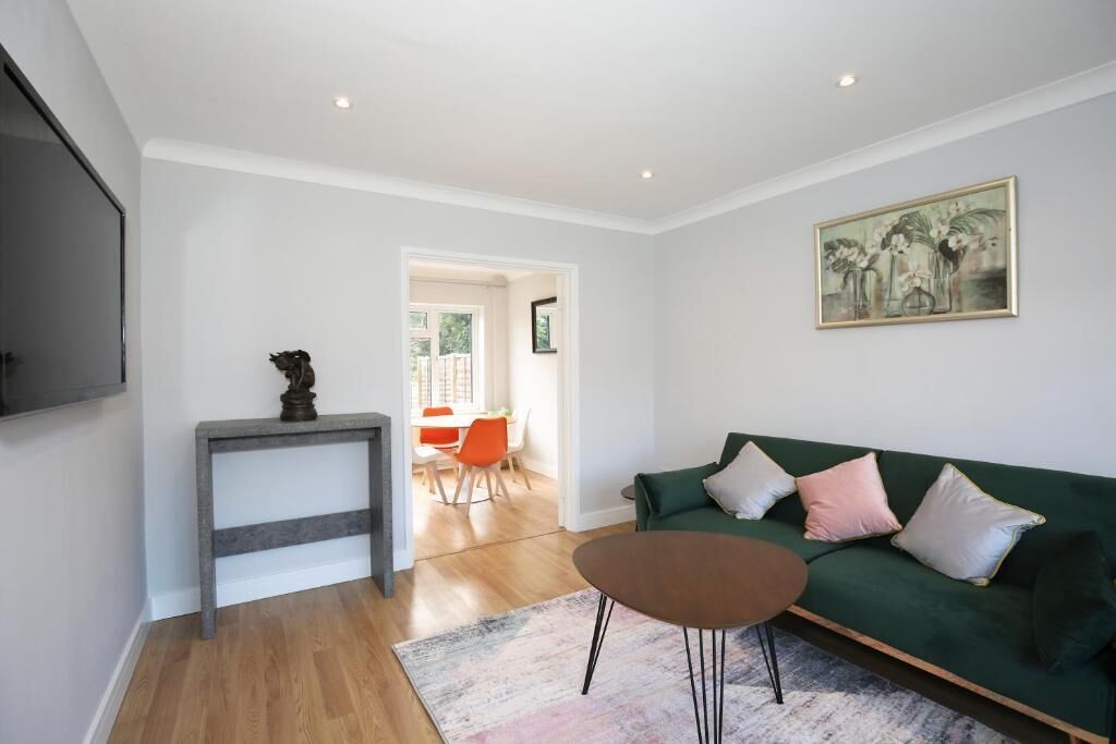 A living room with a green sofa, a small table, and a painting on the wall.
