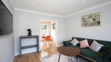 A living room with a green sofa, a small table, and a painting on the wall.