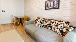 A cozy room with a sofa, a dining table, and two chairs. - Flat balcony overlooking the countryside, close to shops (Ax-les-Thermes)