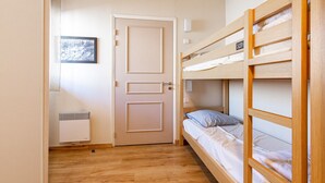 A room with a bunk bed, a door, a radiator, and a framed picture on the wall. - Flat balcony overlooking the countryside, close to shops (Ax-les-Thermes)