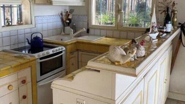Una cucina con una finestra, un fornello e un lavello.