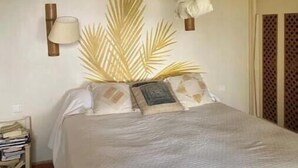Un letto con una coperta bianca, una lampada a sospensione e una lampada fissata al muro.