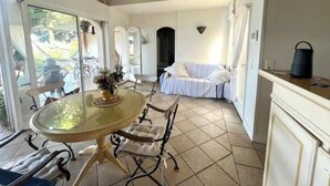 Una stanza con tavolo in vetro, sedie, un letto e vista sull'esterno.