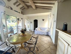 Ein Zimmer mit Glastisch, Stühlen, einem Bett und Blick ins Freie.
