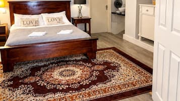 Une chambre à coucher avec un lit en bois, une table de chevet, une lampe et un tapis à motifs.