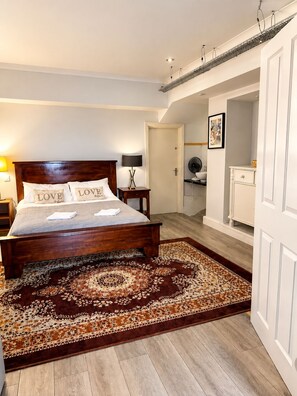 A bedroom with a wooden bed, a nightstand, a lamp, and a patterned rug. - 12A Regency Square (Brighton and Hove)