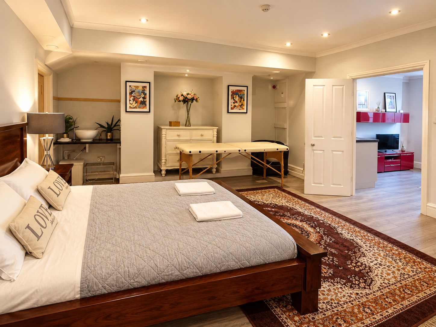 Une chambre à coucher comprenant un lit, des tables de chevet, une commode, un bureau, une chaise, une coiffeuse, un miroir, une porte et un tapis.