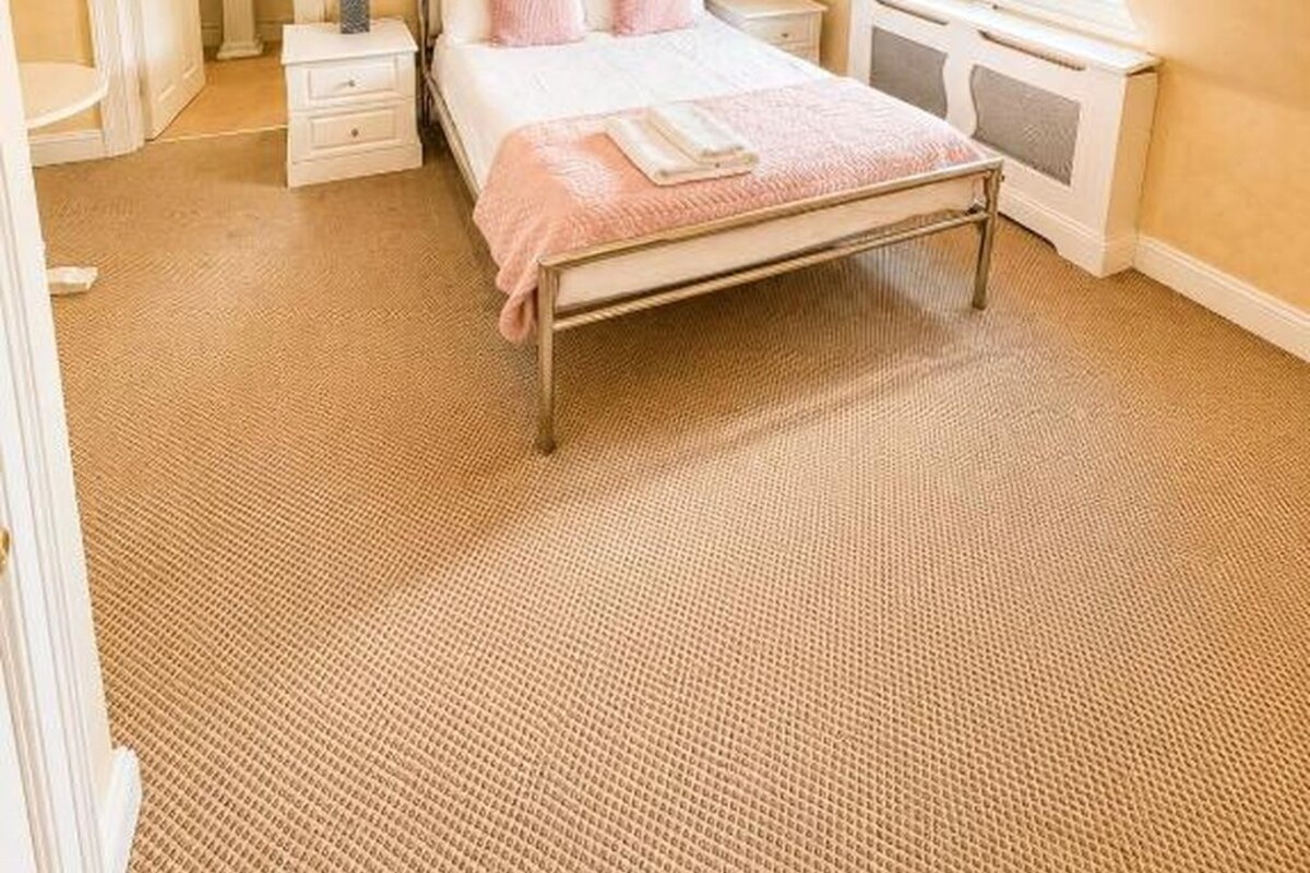 A bedroom with a bed, bedside tables, a dresser, a mirror, and a window.