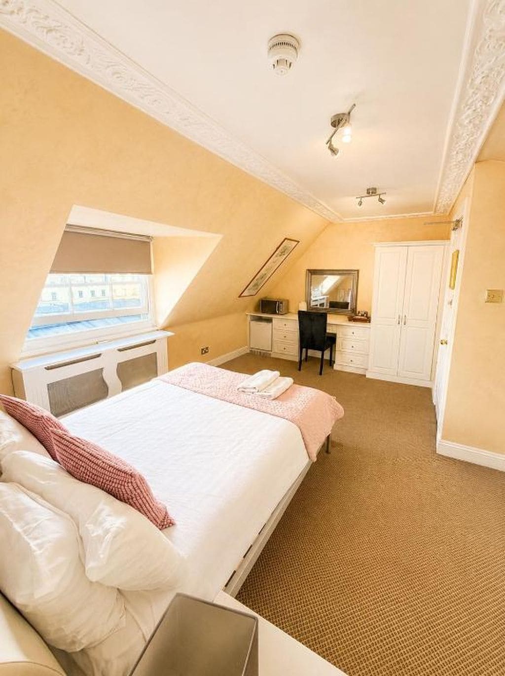 A bedroom with a bed, a desk, a chair, a wardrobe, and a bathroom.